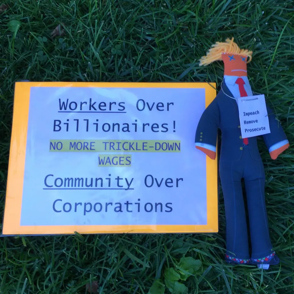 The doll is dressed in a navy blue suit, a white shirt, and a red tie. The doll's hair is bright yellow strands of thin yarn.