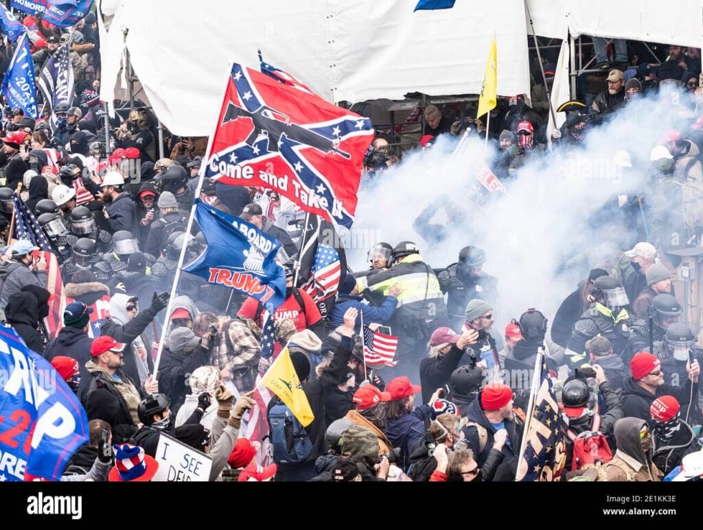 The words on the Confederate Flag are "Come and Take It" with an image of an automatic rifle. The mob is storming the Capitol.